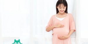 摄图网_501369097_一个孕妇在客厅站着抚摸肚子（企业商用）.jpg